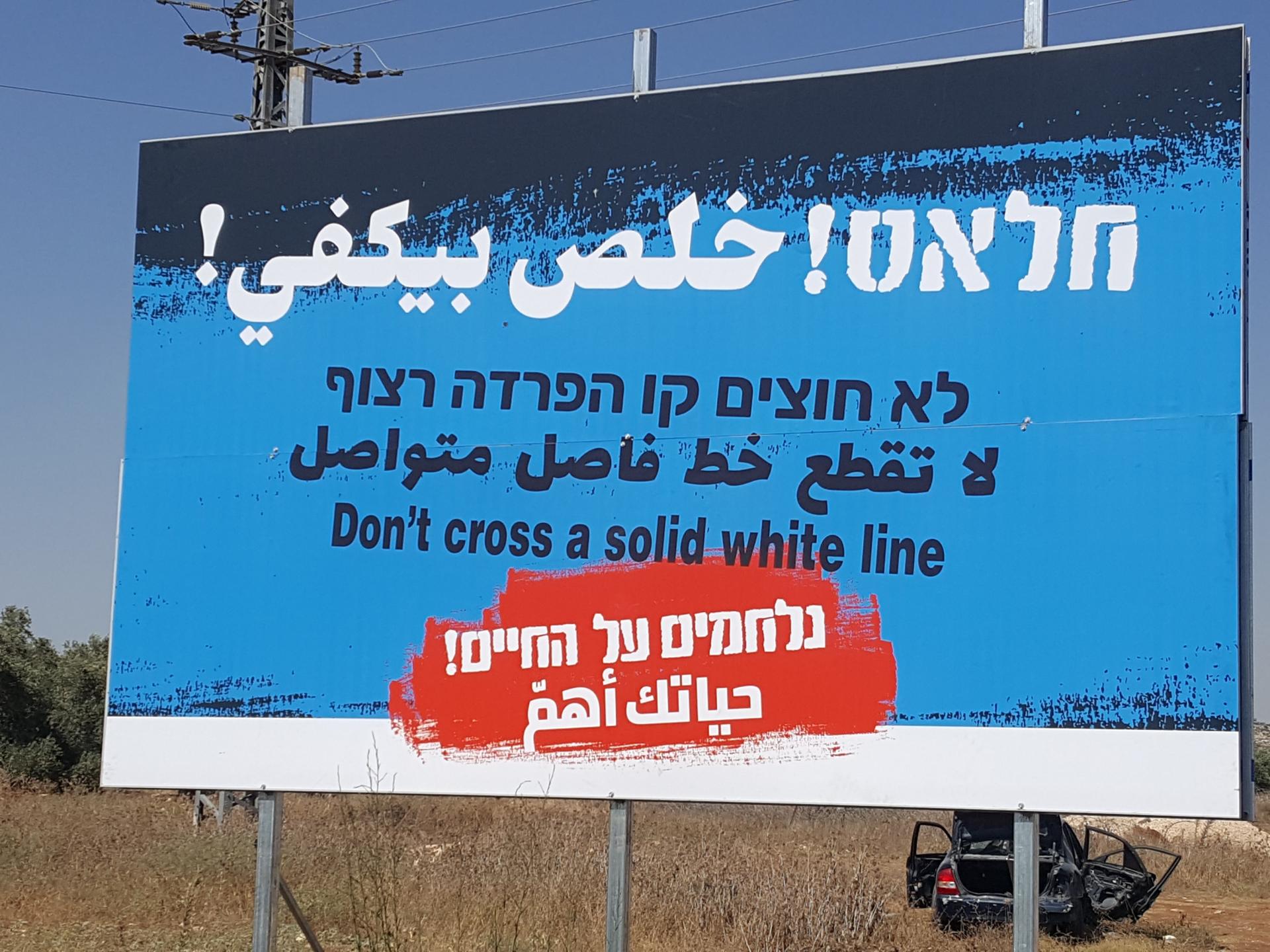 a new sign in Hebrew, Arabic, and English telling drivers not to cross the unbroken line on the road