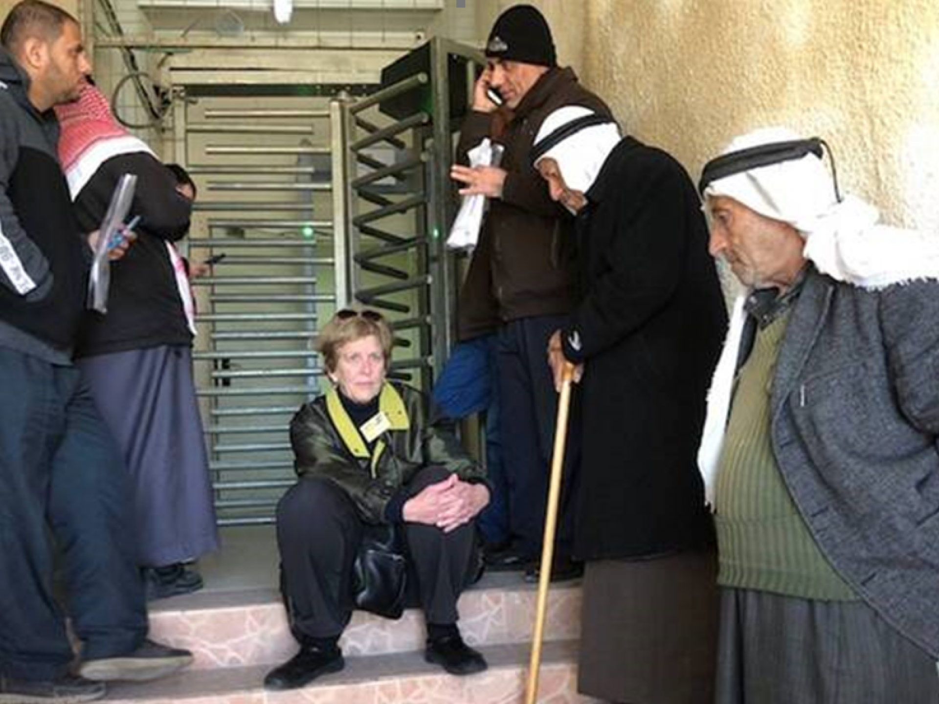 אישה יושבת ליד קרוסלה ומספר גברים פלסטינים לידה