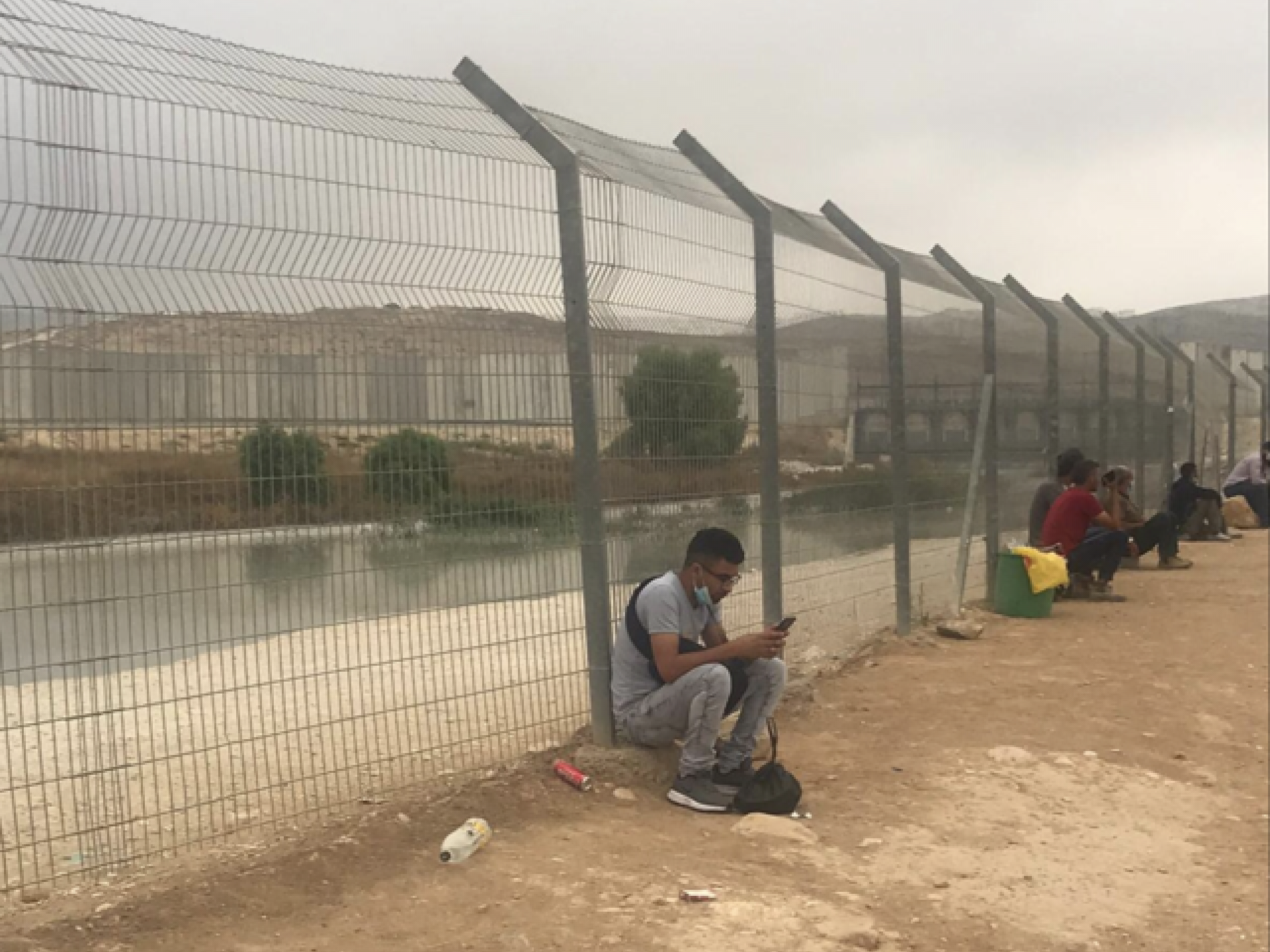 פלסטינים יושבים על גדות נחל הביוב ומחכים להסעה