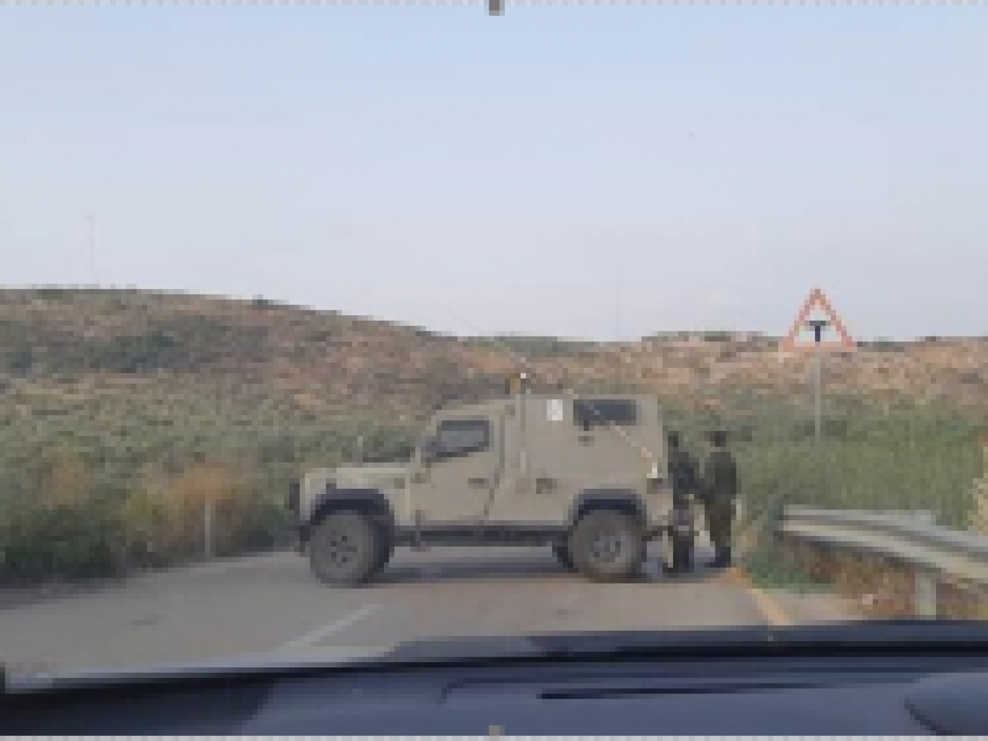 רכב צבאי לרוחב הכביש ושני חיילים