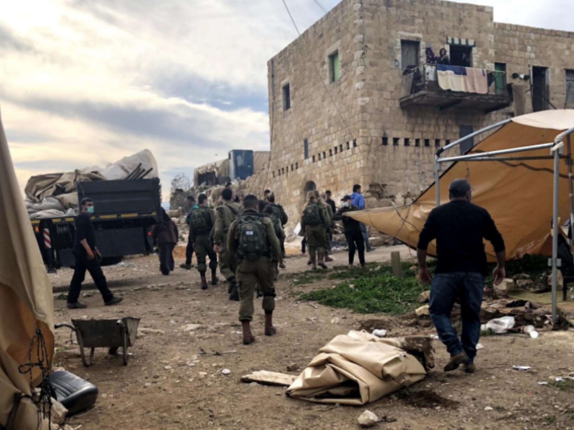 חיילים מסתובביפ בחצר של הפלסטינים ומפרקים סככה לכבשים