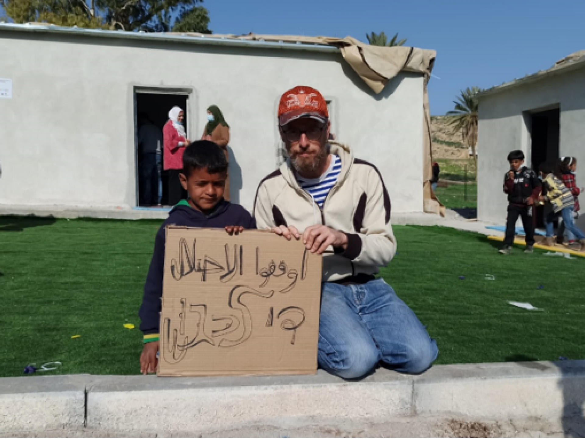 פעיל שלום ותלמיד מחזיקים שט ועליו כתוב בעברית ובערבעת: די כיבוש