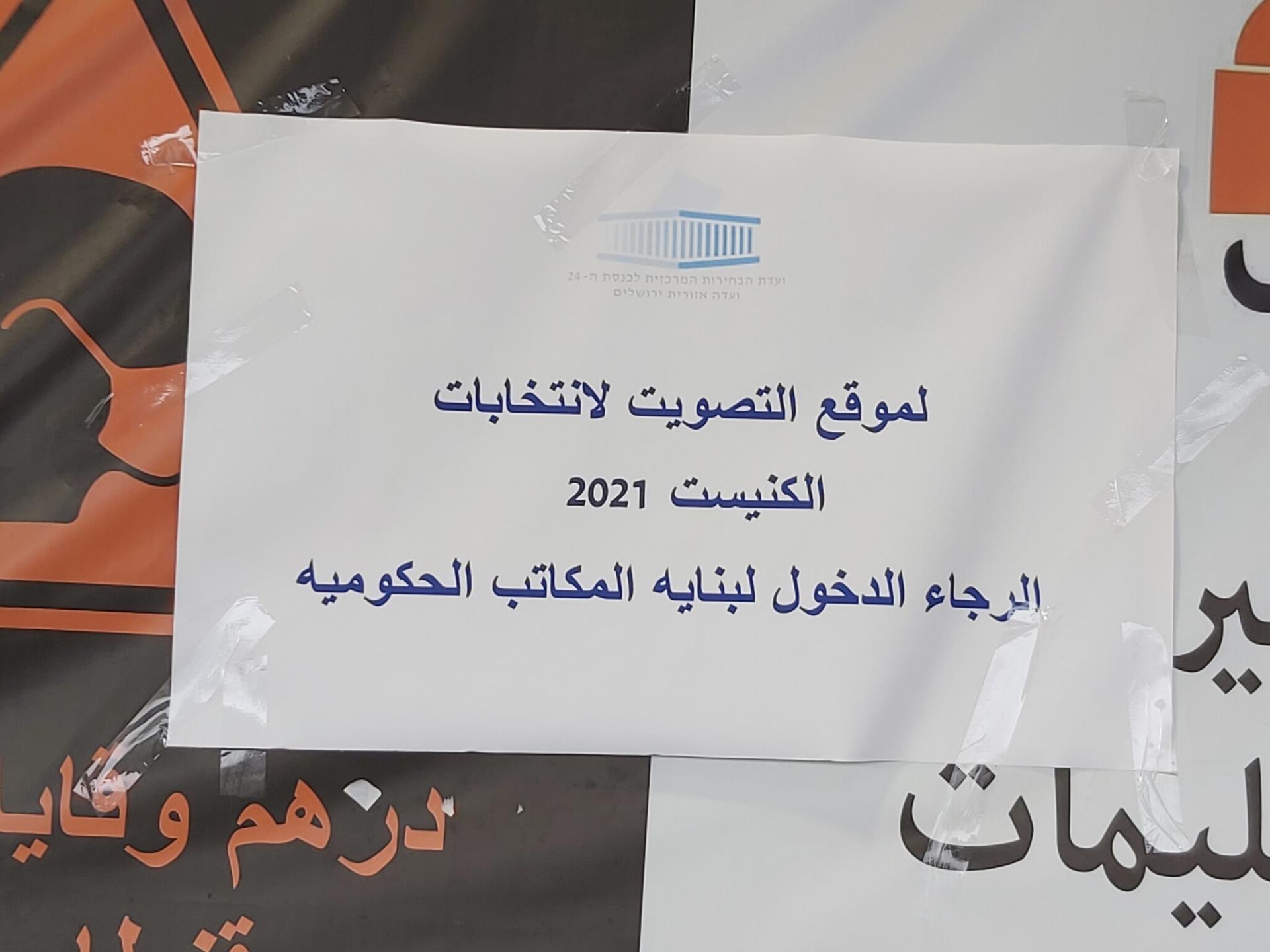 שלט נייר עליו כתוב: לאתר ההצבעה לבחירות/ הכנסת 2021/ אנא הכנס לבניין משרדי הממשלה