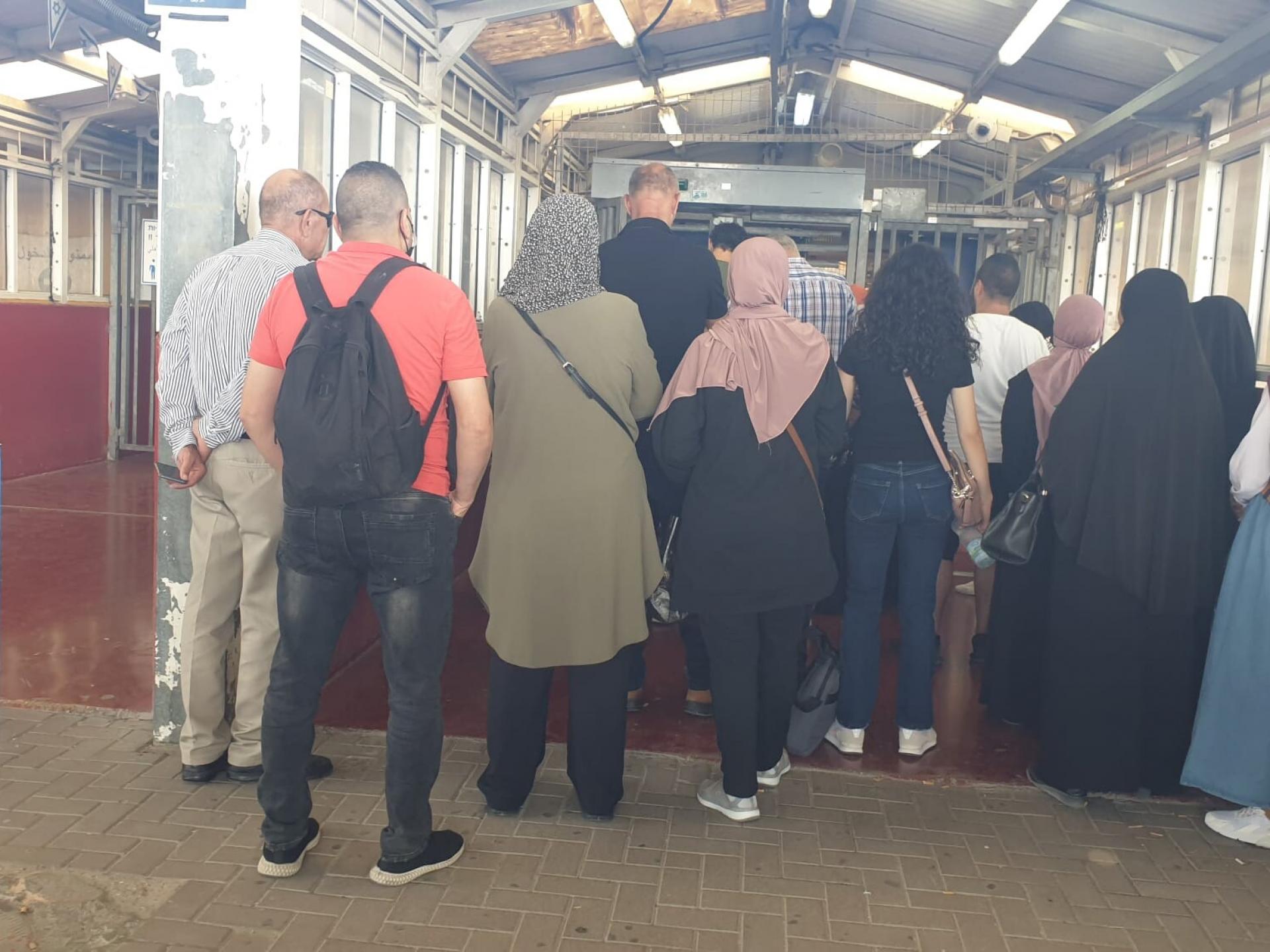 קבוצת פלסטינים ממתינים בתור בתוך מחסום