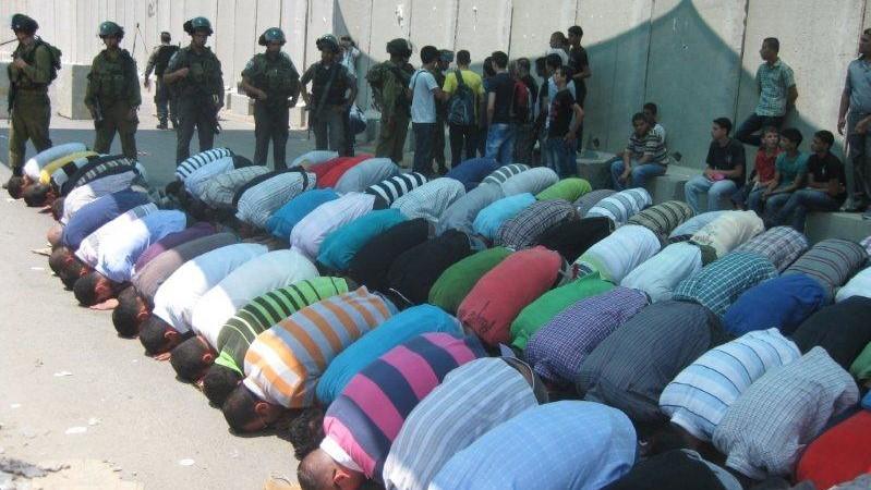 מוסלמים מתפללים וחיילים עומדים לצידם