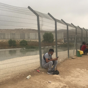 פלסטינים יושבים על גדות נחל הביוב ומחכים להסעה