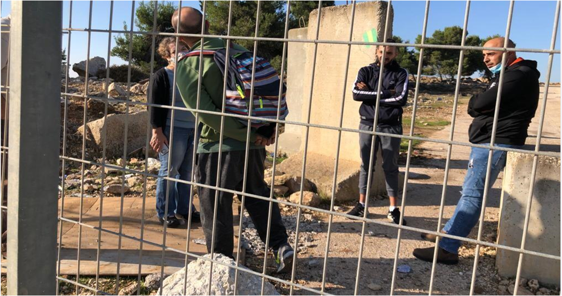 גדר ומעבר לה שלושה גברים משווחים עם אישה