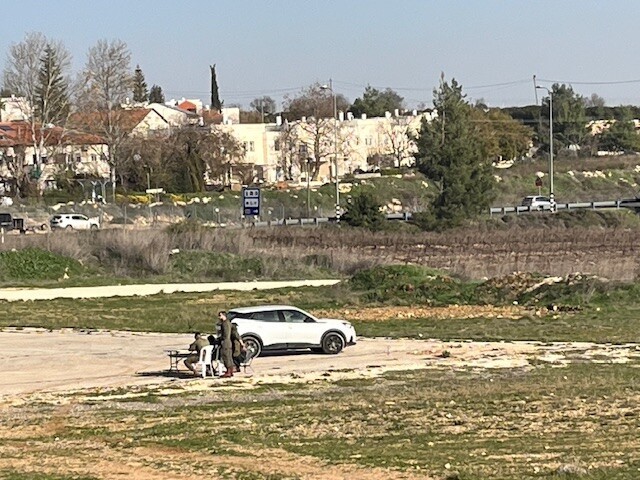Three soldiers are sitting in an empty field, too busy to take care of the Palestinians in the Etzion DCO
