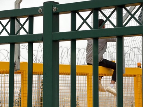 There are iron fences around the checkpoint with barbed wire on top.