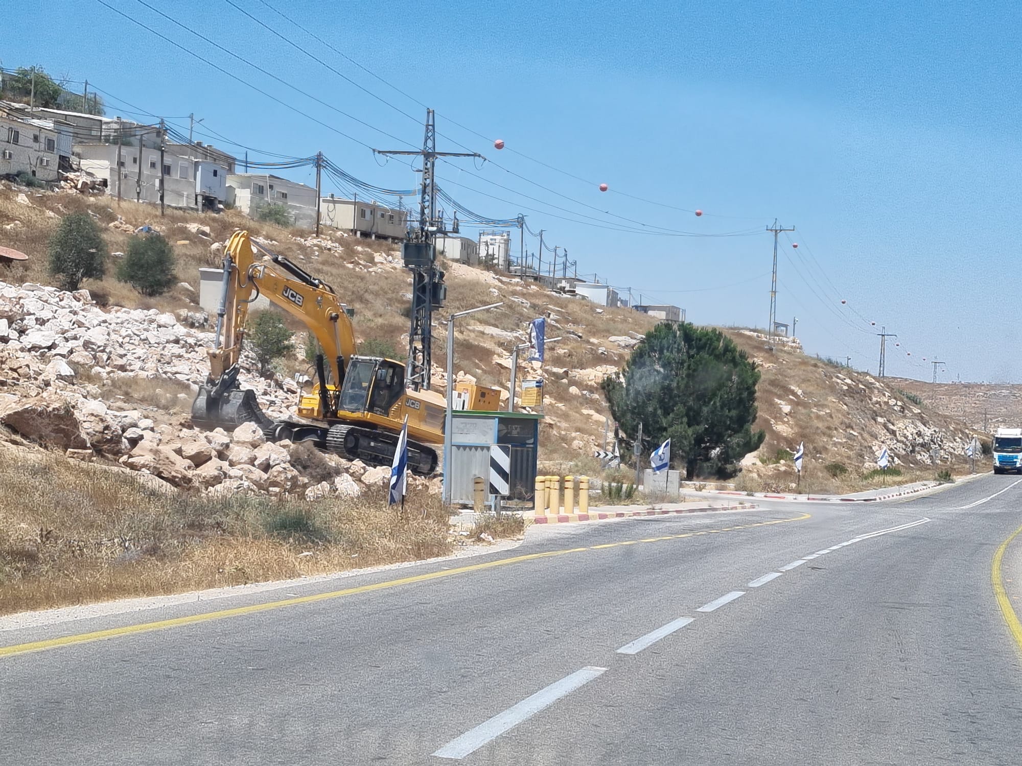 A bulldozer clears stones and levels a road in Asael on Highway 317, southern Hebron Hills