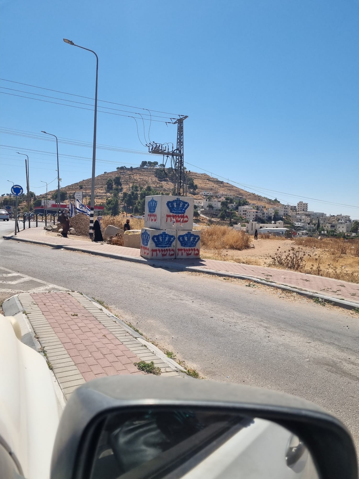 קילומטרים עם בטונדות ועליהן הגרפיטי "משיח", בתוך ים דגלי ישראל, בדרום הר חברון