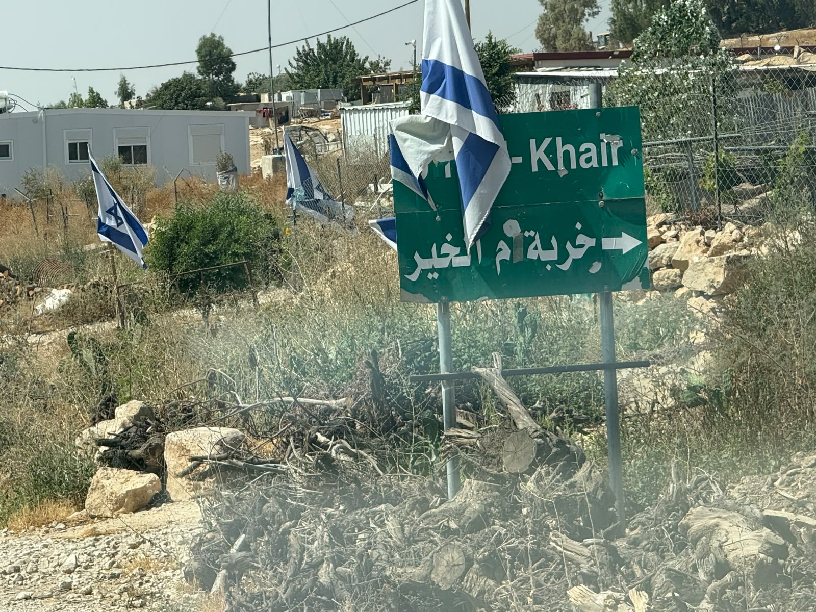 The Israeli flag was placed on the entrance sign to Umm al-Khair, with other flags scattered around.