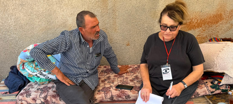 A MachsomWatch volunteer sits in conversation with a Palestinian man in the South Hebron Hills.