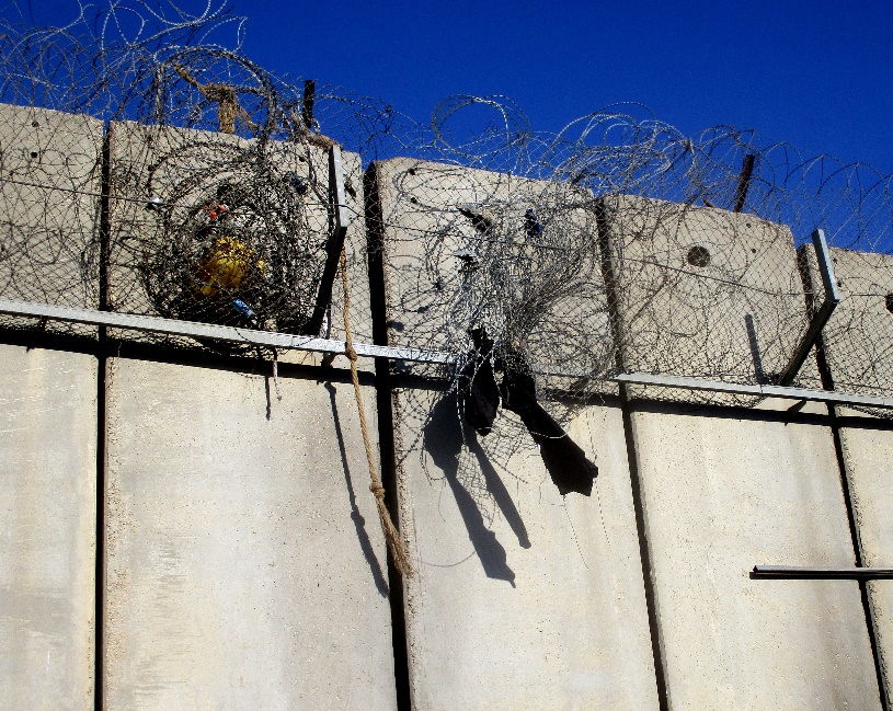 Qalandiya. Remnants of clothing caught on the barbed wire at the top of the wall